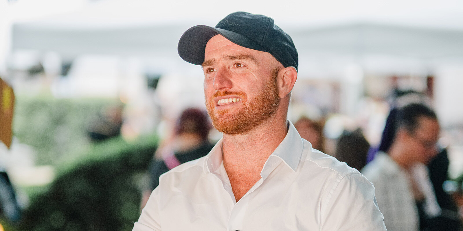 Junger Mann mit Basecap lächelt in die Kamera.