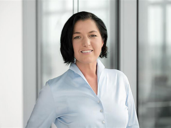 Eine Frau mit dunklen Haaren und heller Bluse.